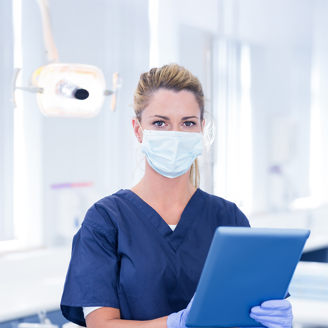 Dentista con in mano un tablet all'interno di uno studio dentistico